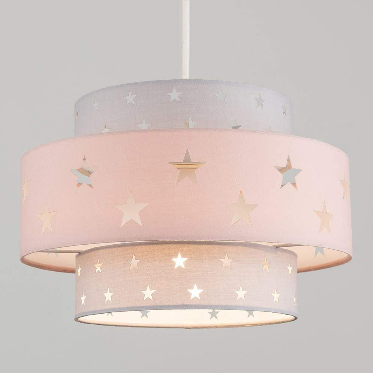 Our grey and pink two tiered star shade features a mixture of large and small sweet stars cut out across a grey and pink background. When your lamp is turned on it will shine out through these cut-outs, mimicking a beautiful night sky. This lampshade is made with soft-touch fabric for a little bit of luxury.