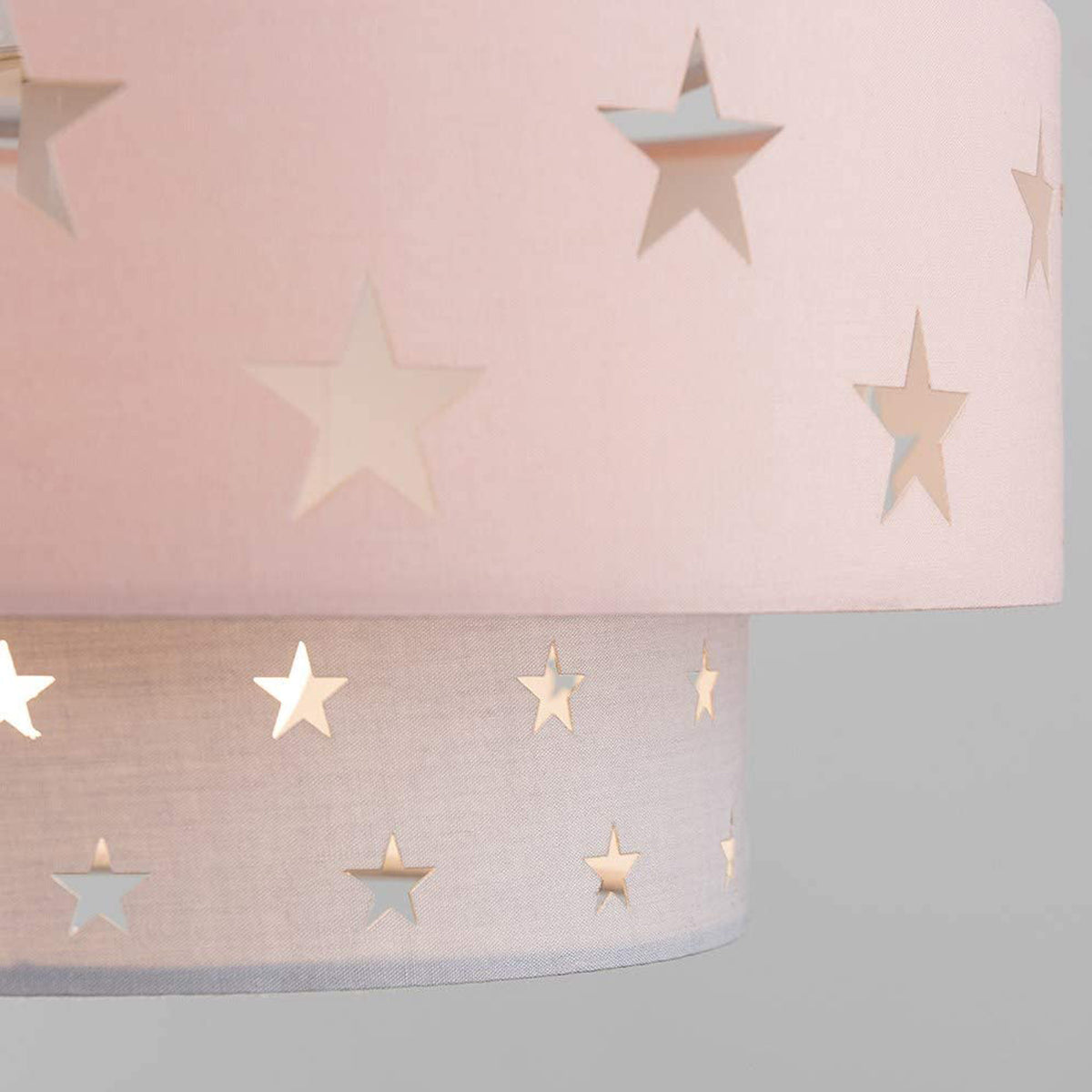 Our grey and pink two tiered star shade features a mixture of large and small sweet stars cut out across a grey and pink background. When your lamp is turned on it will shine out through these cut-outs, mimicking a beautiful night sky. This lampshade is made with soft-touch fabric for a little bit of luxury.