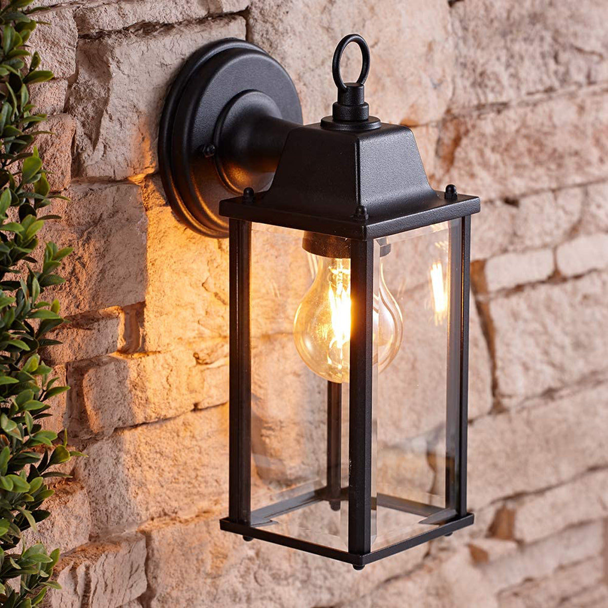 Shot of CGC Interior’s FREYA black bevelled glass coach lantern wall light fixed onto brick wall with lights on inside the box